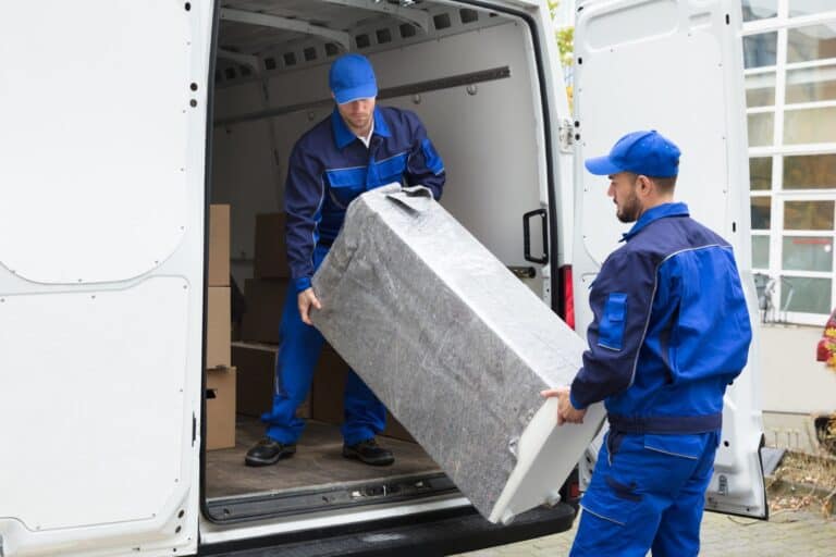 A man and van loading an appliance to the van in the concept of house removals