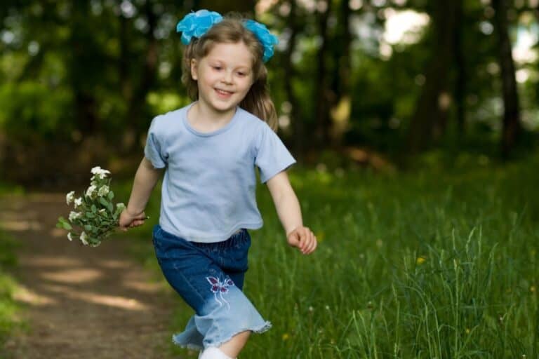 A happy young girl running in the park while holding flowers in the concept of 'best parks and green spaces in Orpington'.