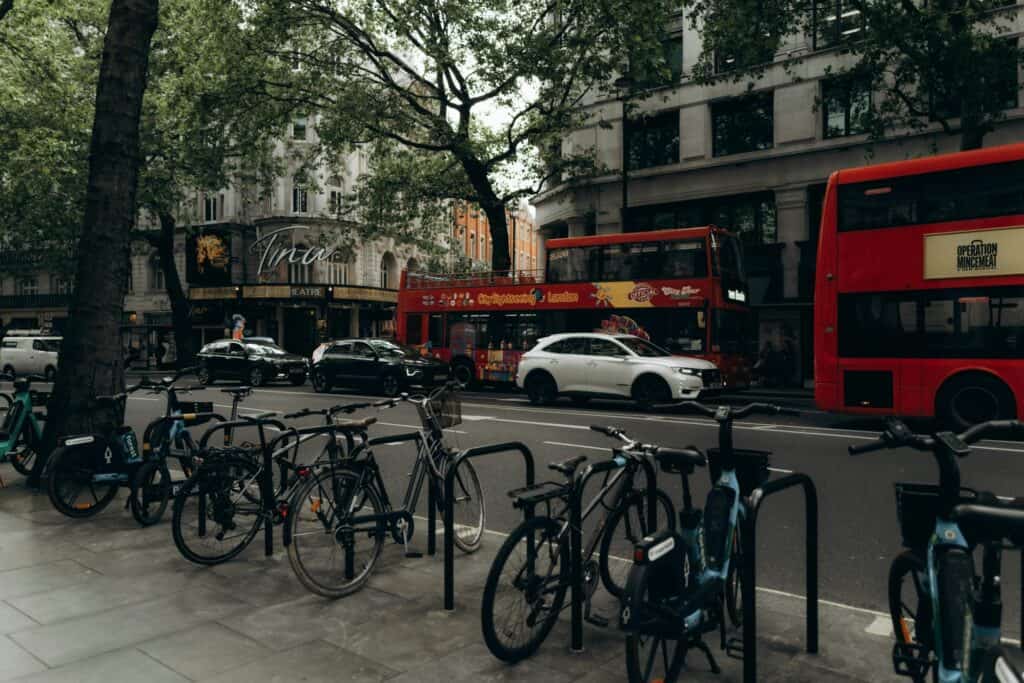 Parked bicycles on the side of the street while buses, taxis, and cars share the road in the concept of 'how to use Orpington's public transport'.