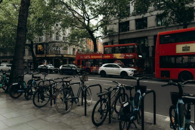 Parked bicycles on the side of the street while buses, taxis, and cars share the road in the concept of 'how to use Orpington's public transport'.