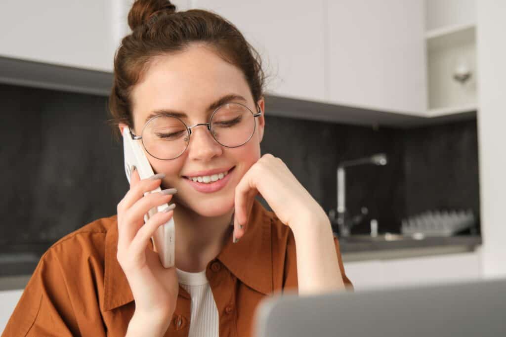 Closeup of a young woman in the kitchen speaking on the phone in the concept of 'How to Get a Quote for a Man and Van Service in Orpington'.